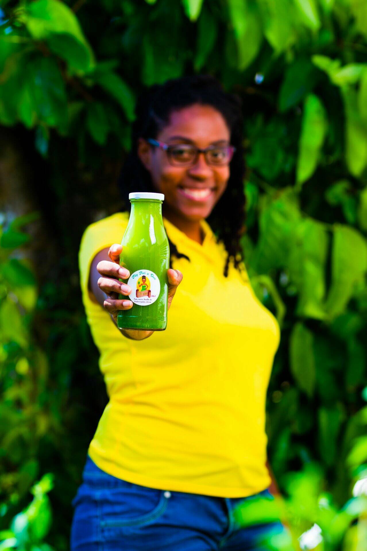 Portrait de Gladys tenant une bouteille de jus de feuilles de fruit à pain