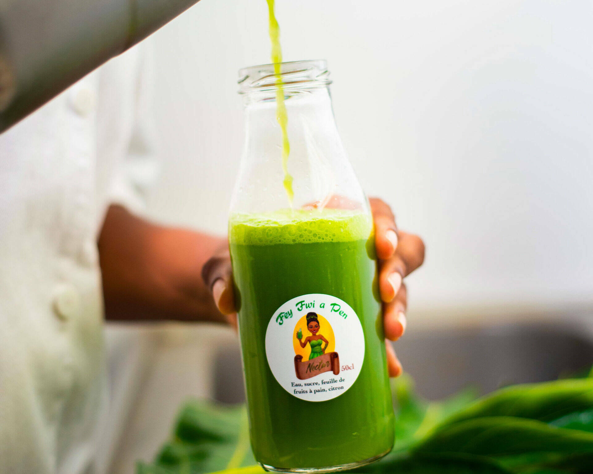 Gladys verse du jus de feuille de fruit à pain dans une bouteille