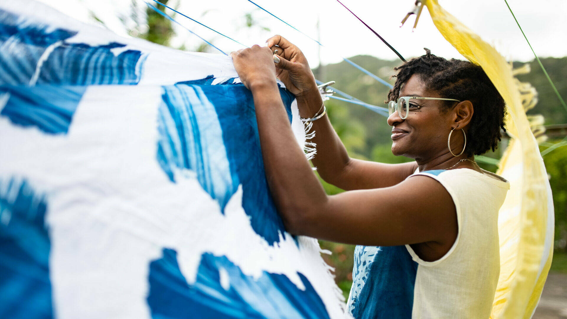 Portrait de Ghislaine en train d'étendre un de ses paréos sur une ligne