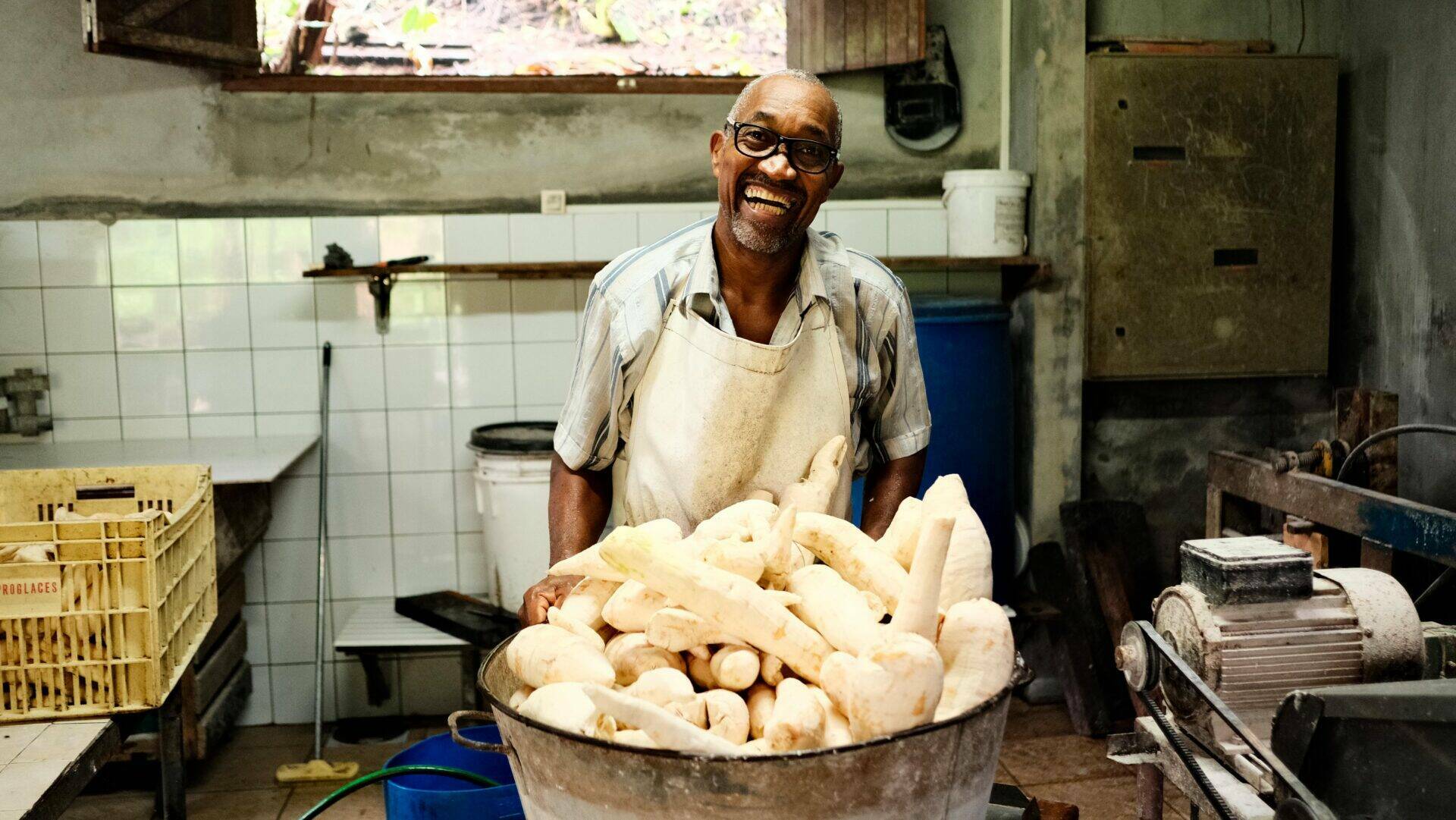 Portrait de Jean-Charles posant derrière une grosse bassine de maniocs